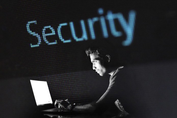 Fraude no mercado. Homem mexendo no computador e na parte de cima da imagem está escrito segurança na língua inglesa.