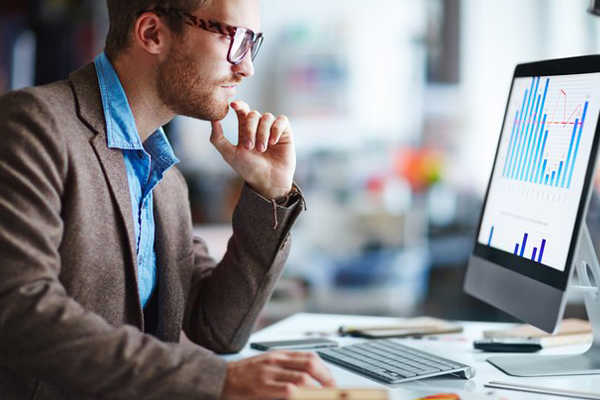 Como qualificar clientes com análises de crédito. Homem sentado em frente ao computador e trabalhando.