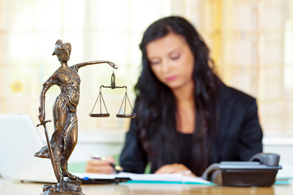 localização de pessoas para escritório de advocacia. Mulher concentrada lendo alguns papéis em cima da mesa e uma estátua simbolizando o a profissão de advocacia.