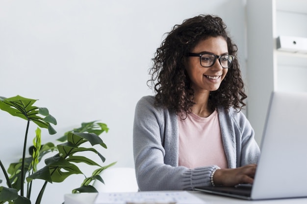 Relatório de análise de crédito. Mulher jovem trabalhando com o auxílio do computador e sorrindo.